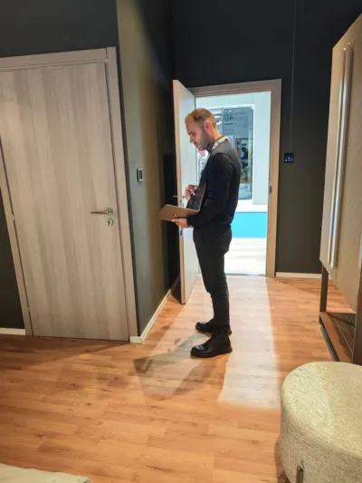 Man with a laptop testing room controls in a hotel room mock-up on an exhibition stand