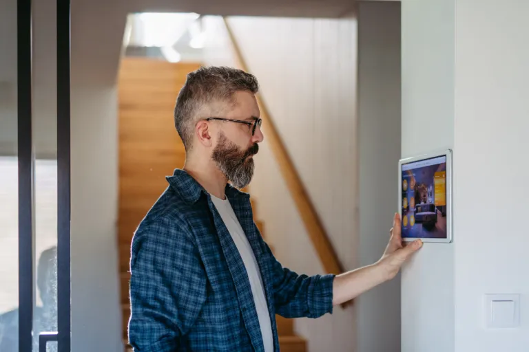 A man using a wall panel to control his smart home